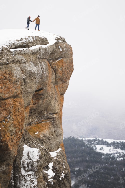Preview: People standing on edge of mountain cliff, fog and snow around