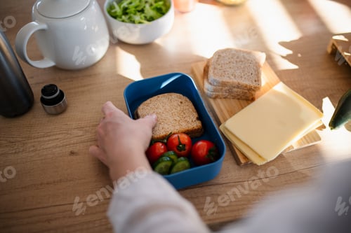 Preview: Close-up of mother preparing snack to lunch box in kitchen at home