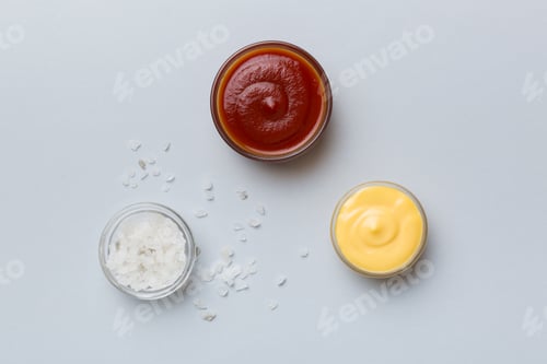 Preview: Bowl of salt, ketchup and cheese sauce on colored background, top view with copy space