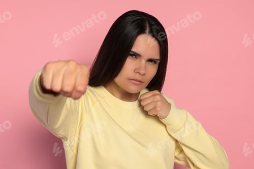 Preview: Young woman ready to fight on pink background