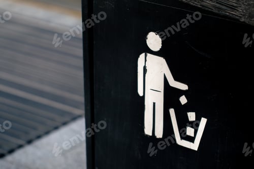 Preview: close-up of a black iron trash can with a stretched black garbage bag with a white drawn icon of a