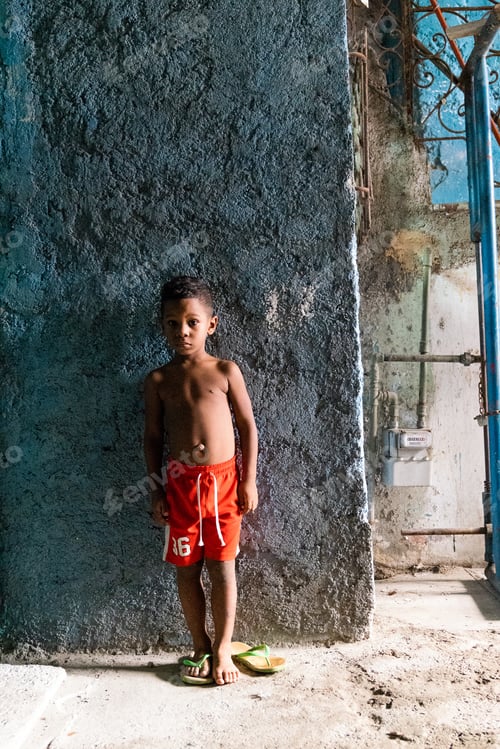 Preview: LA HABANA, CUBA - NOVEMBER, 6 , 2018: Poor Hispanic child standing near wall
