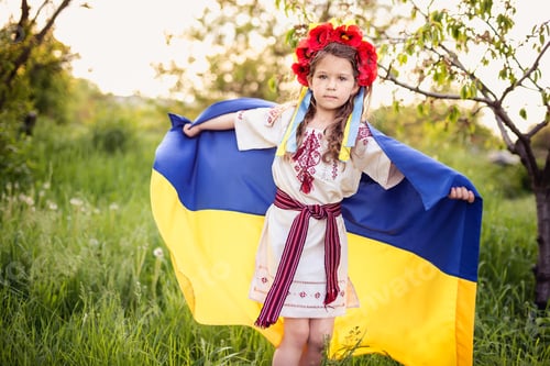 Preview: Ukrainian child girl in embroidered shirt vyshyvanka with yellow and blue flag of Ukraine in field.