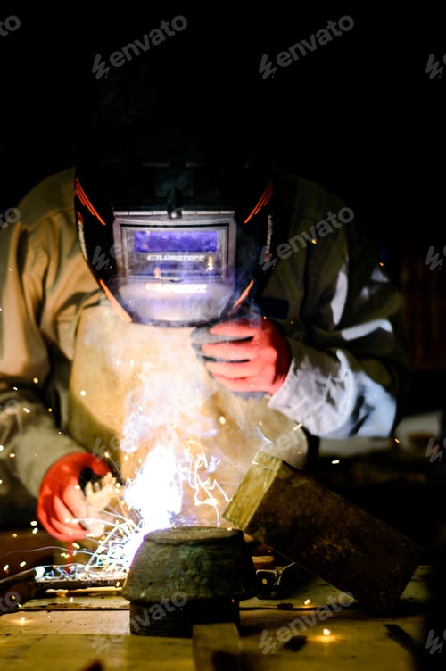 Preview: Unrecognizable person wearing a helmet and welding in the personal garage