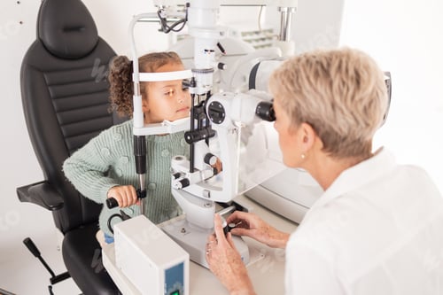 Preview: Girl child in eye exam for vision, woman optician checking kids eyes in consultation room and medic