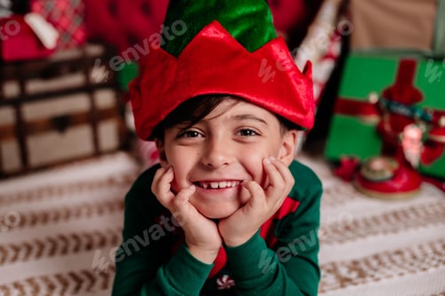 Preview: Cheerful child in a festive elf costume, surrounded by Christmas gifts