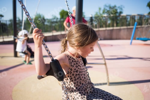 Preview: playground in summer with children. girl swinging on a chain swing