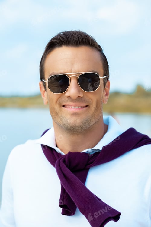 Preview: portrait of smiling man in sunglasses looking at camera with river on background
