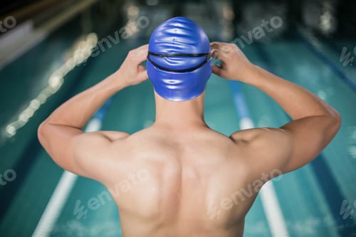 Preview: Fit man adjusting his goggles at the pool
