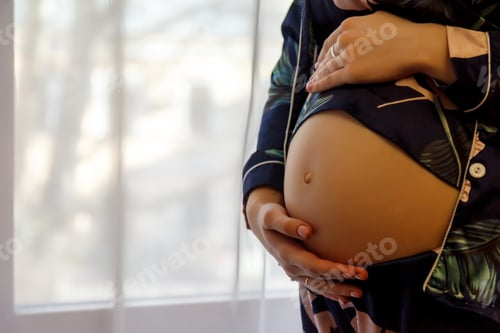 Preview: Belly of a pregnant woman at a light window