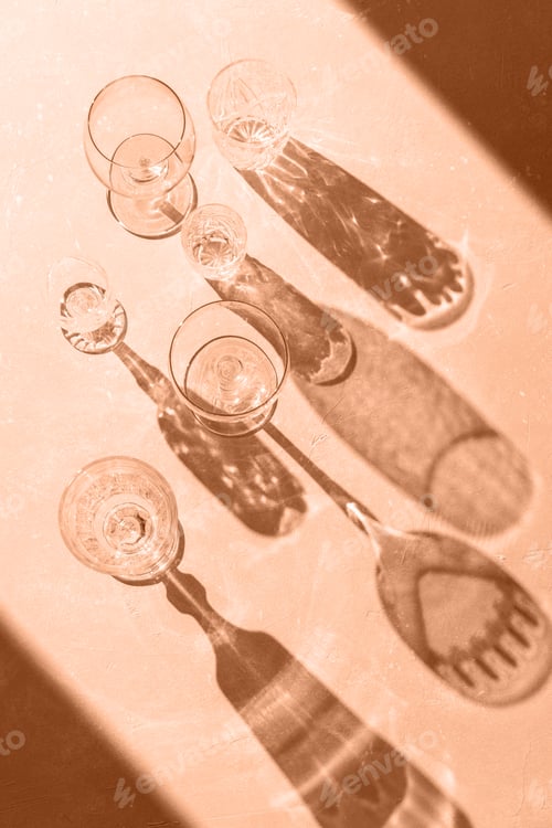 Preview: Variety of empty glasses on peach background with trendy hard shadows and sun light.