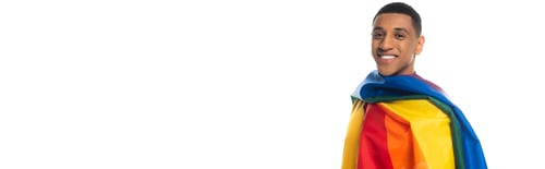 Preview: young african american man, covered with lgbt flag, smiling at camera isolated on white, banner