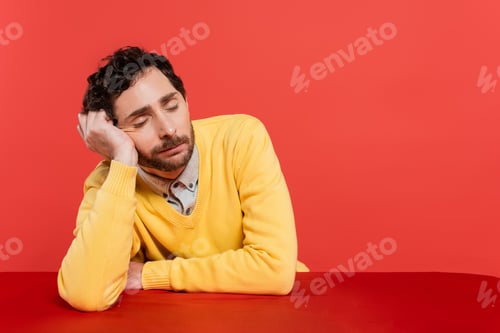 Preview: tired man in yellow long sleeve jumper sleeping at desk isolated on coral background