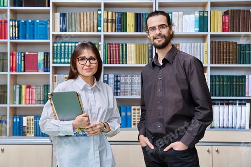 Preview: Portrait of man and woman colleagues educators teachers inside classroom library