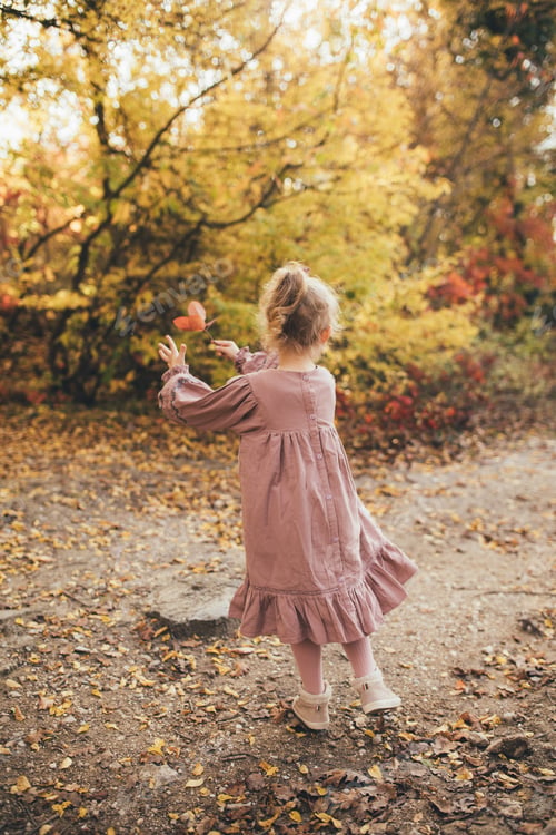 Preview: Cute little girl wearing beautiful dress having fun in autumn forest