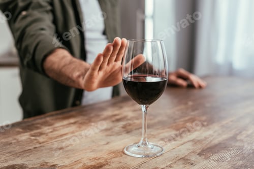 Preview: Cropped view of man pulling hand to wine glass on table