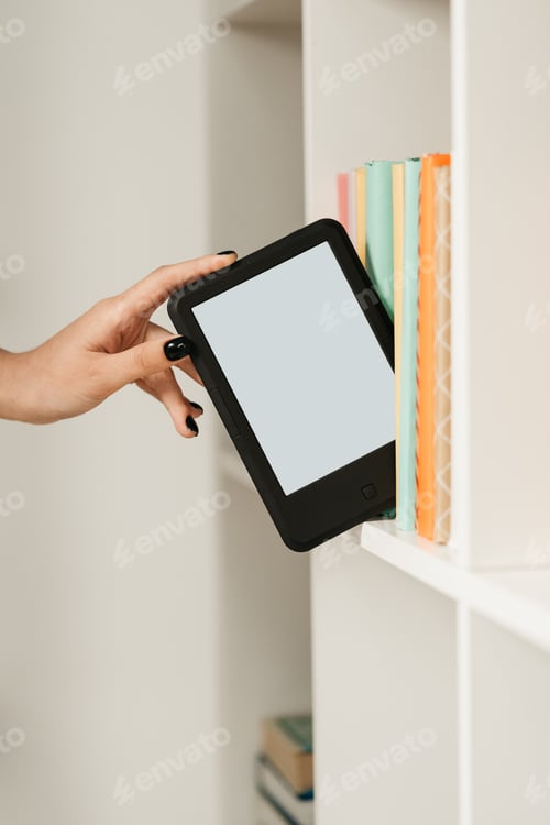 Preview: Man taking modern e-book reader from a bookshelf close up