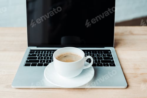 Preview: cup of coffee on laptop with blank screen in office