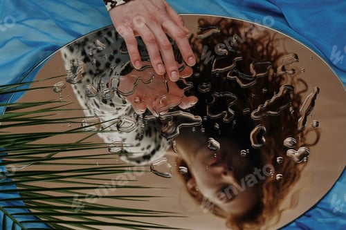 Preview: Woman touching her reflection in mirror