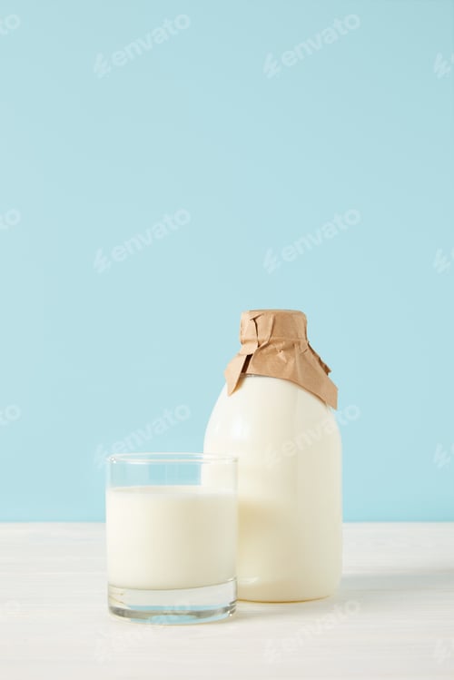 Preview: closeup shot of milk glass and milk in bottle wrapped by paper on blue background