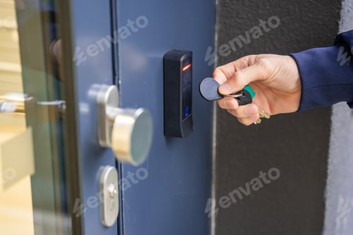 Preview: Close up view of person using a electric lock key fob to access a building via a reader of entry