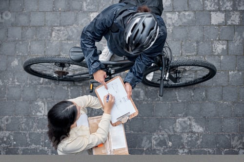 Preview: Bicycle delivery, woman with package from above and signing for box from online shopping website. L
