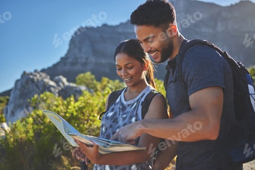 Preview: Shot of a young couple using a guide book to complete a hike in a mountain range