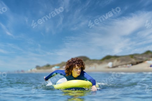 Preview: Fit woman on paddleboard rowing with hands in ocean