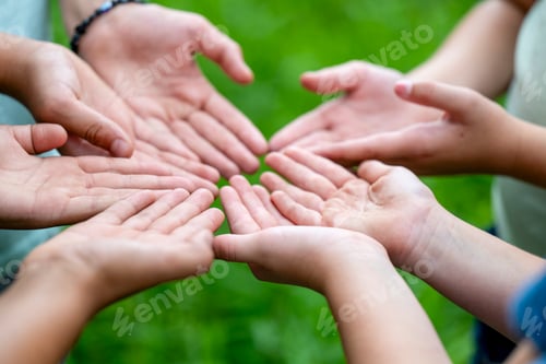Preview: Open hands of several people extended towards each other against a green blurred background.