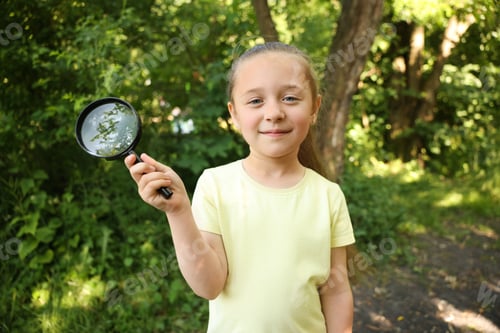 Preview: Cute little girl with magnifying glass in nature