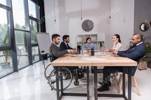 Preview: multicultural group of businesspeople discussing new idea while sitting at table in office