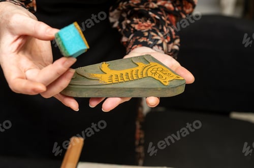 Preview: Female adult holding handmade wooden printing block with yellow cat design