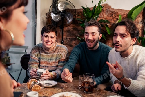 Preview: Young friends enjoying cozy conversation at cafe table with hot drinks