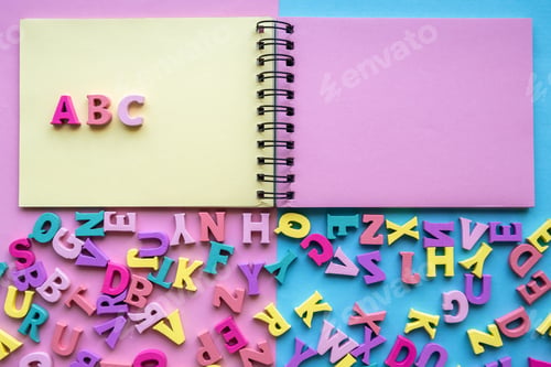 Preview: A set of letters and a notebook for studying the alphabet. Multicolored wooden letters. Top view.