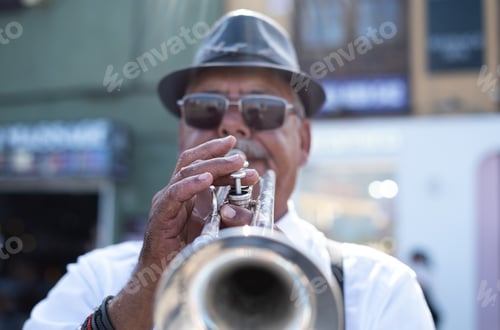 Preview: Jazz artist outdoors concert. A mature man with black hat playing a trumpet in the street