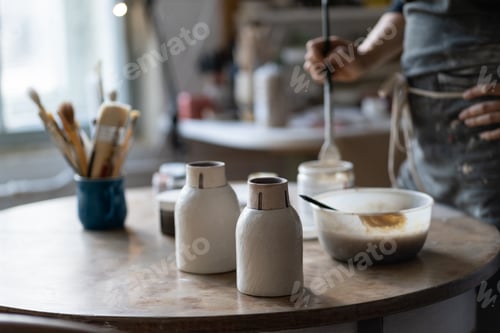 Preview: Crop photo of master leaving clay vases to dry out on round table in shop closeup