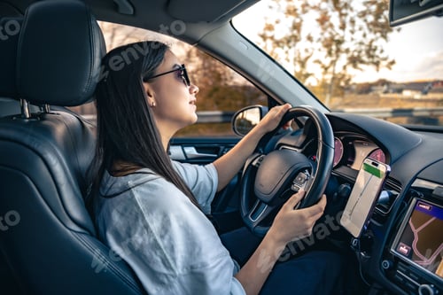 Preview: An attractive young woman driving a car uses a navigator.