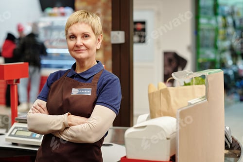 Preview: Confident mature saleswoman in uniform looking at camera