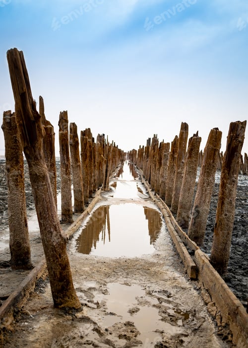 Preview: Beautiful salt lake with blue and pink water and wooden pillars.