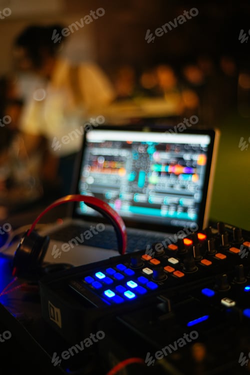Preview: Selective focus vertical shot of a disc jockey sound mixer and a laptop screen at night club