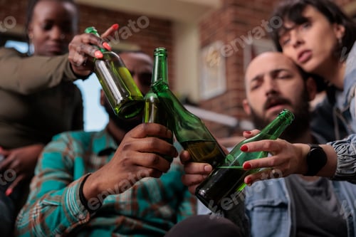 Preview: Multiethnic group of friends saying cheers and clinking beer bottles