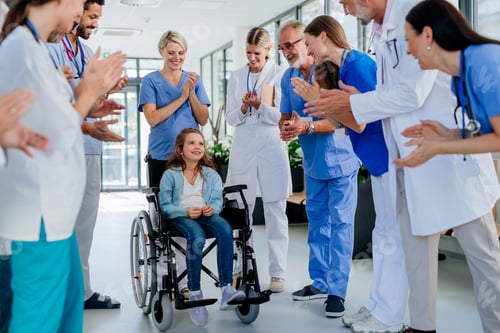 Preview: Medical staff clapping to little girl patient who recovered from serious illness.