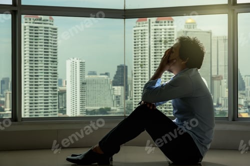 Preview: depressed man sitting head in hands on the interior Skyscraper with low light environment
