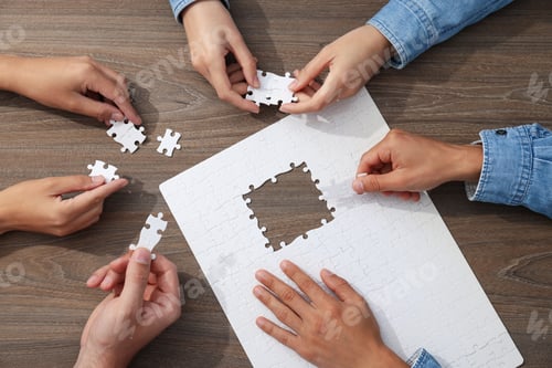 Preview: White puzzles and hands on wooden background