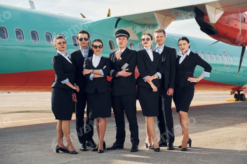 Preview: Posing for a camera. Crew of airport and plane workers in formal clothes standing outdoors together