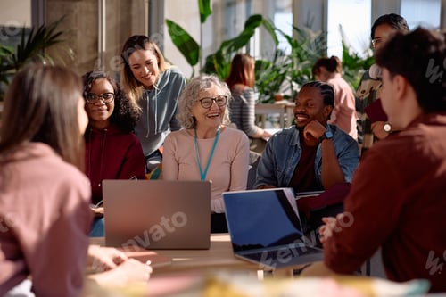 Preview: Group of happy students talking to their teacher while learning at campus.