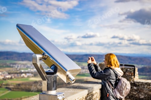 Preview: Woman takes pictures of city Singen from observation deck with telescope of castle Hochnetwil