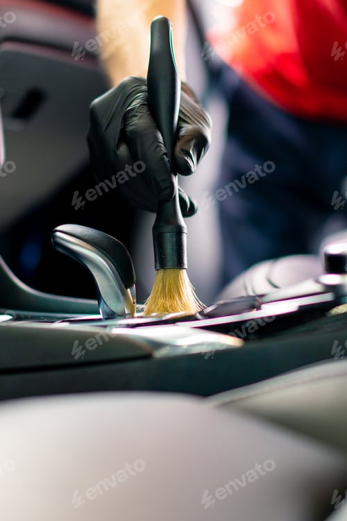 Preview: Car wash worker thoroughly cleaning the interior of a luxury car with a brush gear box,