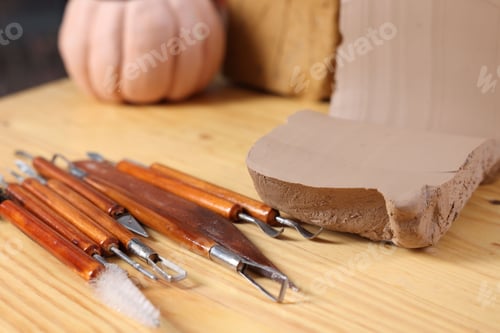 Preview: Set of different crafting tools and pieces of clay on wooden table, closeup