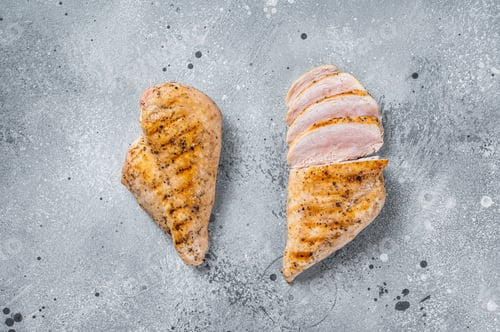 Preview: BBQ grilled and sliced chicken breast fillet steak. Gray background. Top view